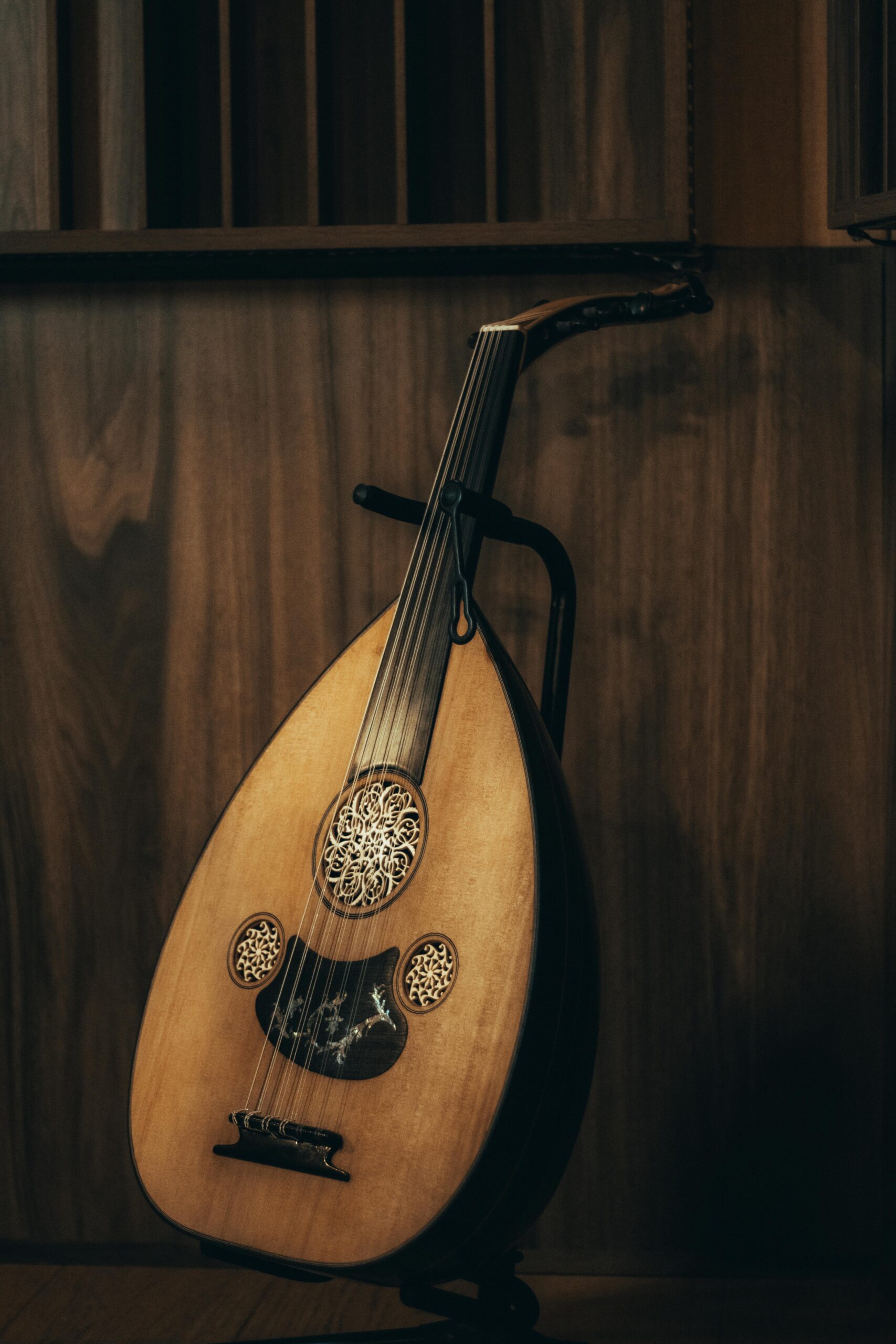A close-up of a traditional oud, showcasing intricate details against a wooden backdrop.