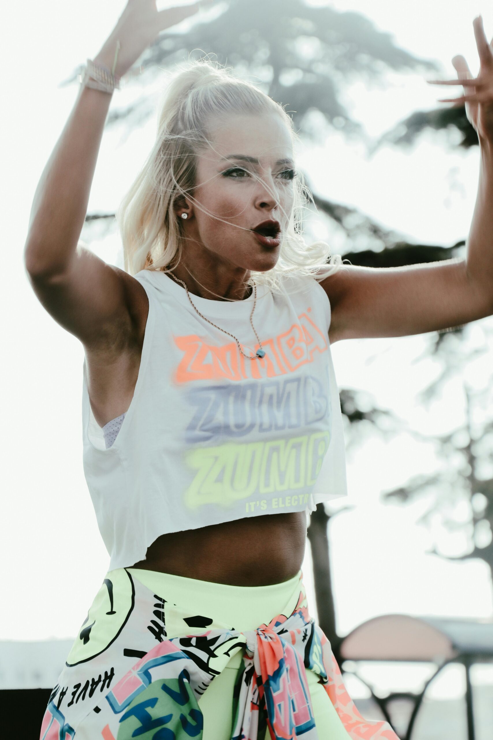 A lively caucasian woman dances energetically outdoors, exuding enthusiasm and vitality.