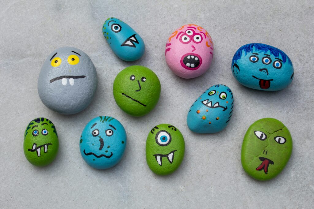Vibrant hand-painted rocks with monster faces, perfect for creative Halloween crafts and indoor fun.