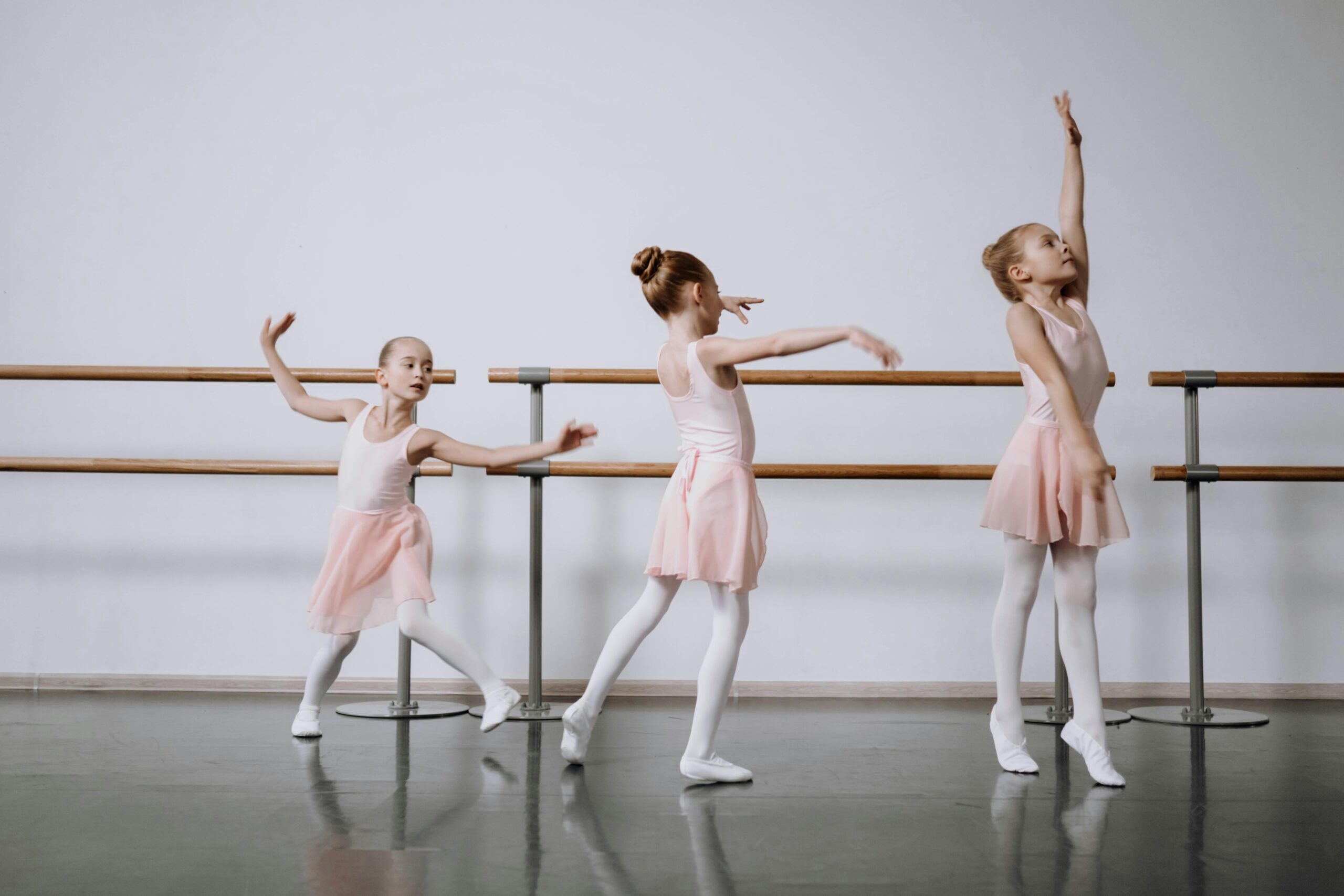 Three young ballerinas practicing ballet in a studio, showcasing grace and poise.