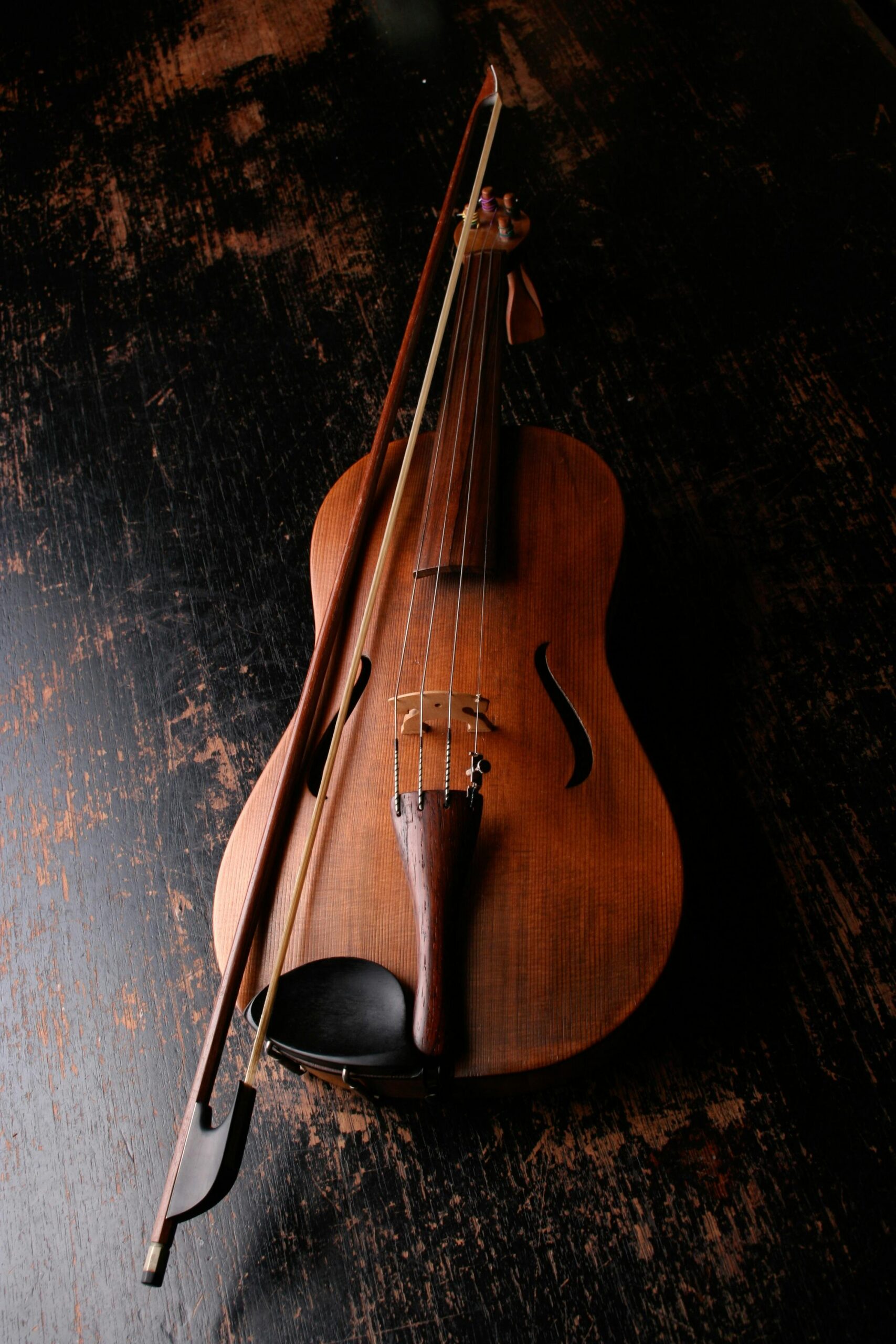 A beautifully crafted violin rests on a dark wooden surface, evoking a classic and artistic mood.